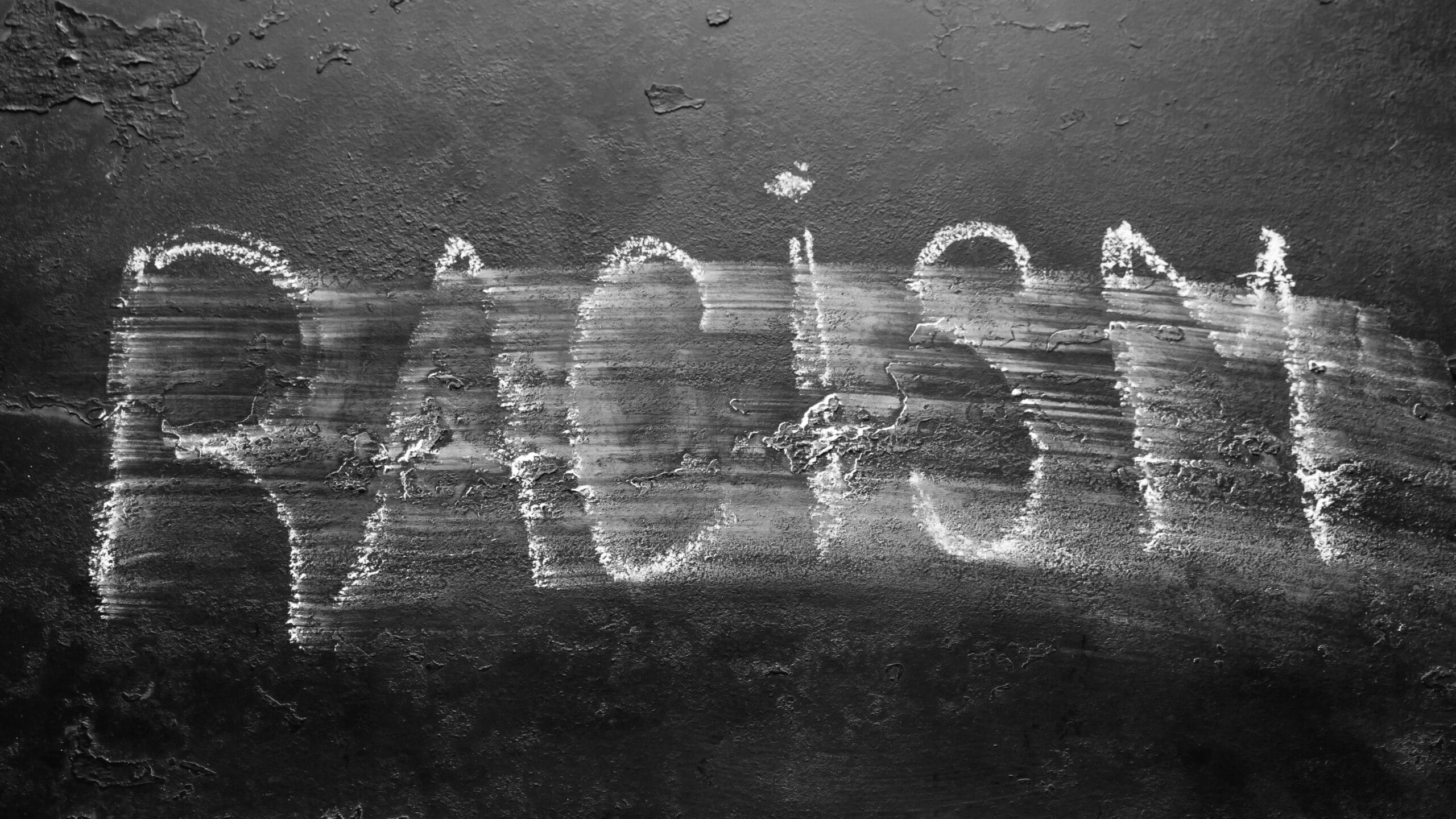 Image of blackboard with the word "racism" in chalk which has been partially wiped out.