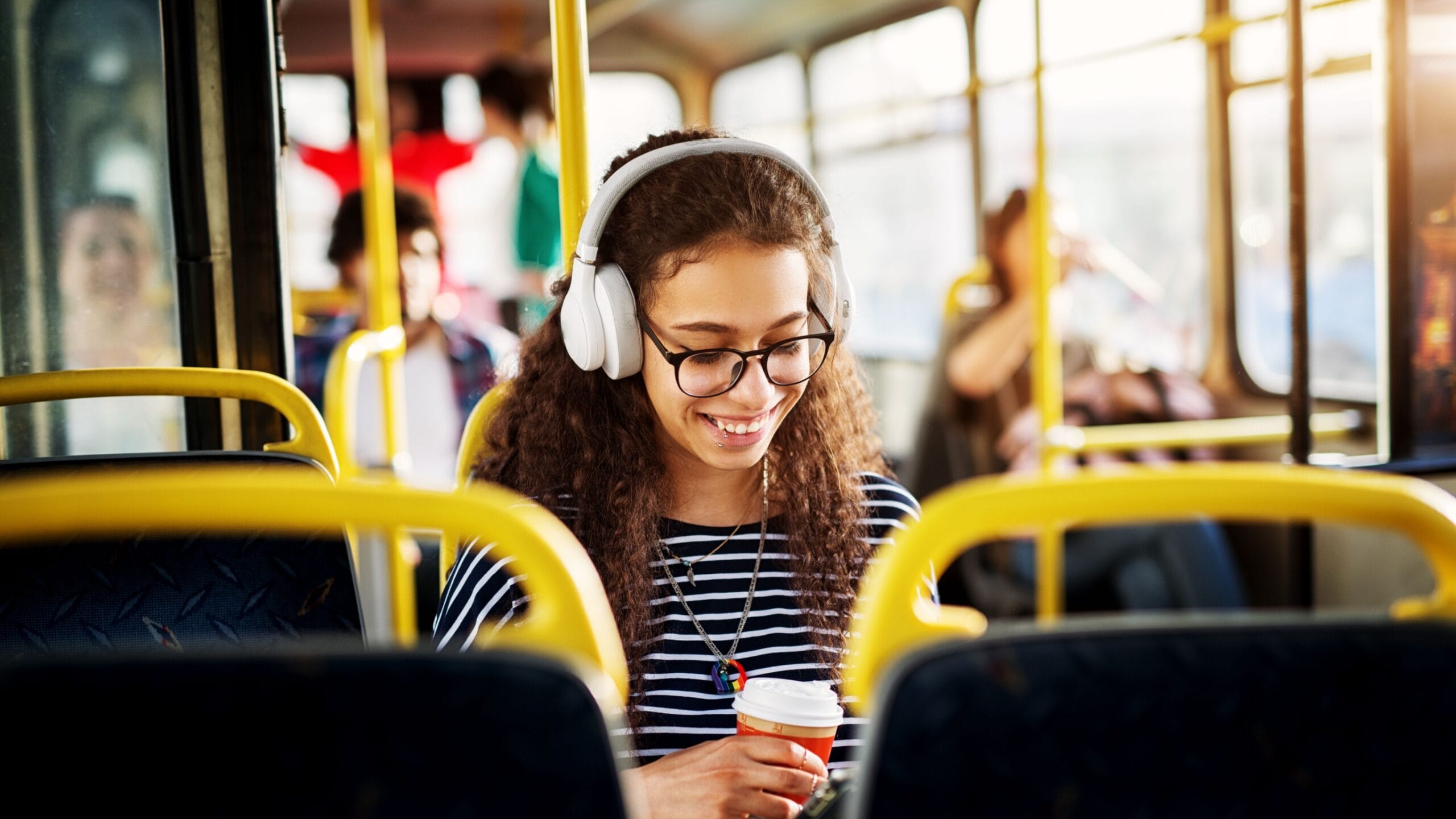 A happy commuter student on a bus with headphones on.