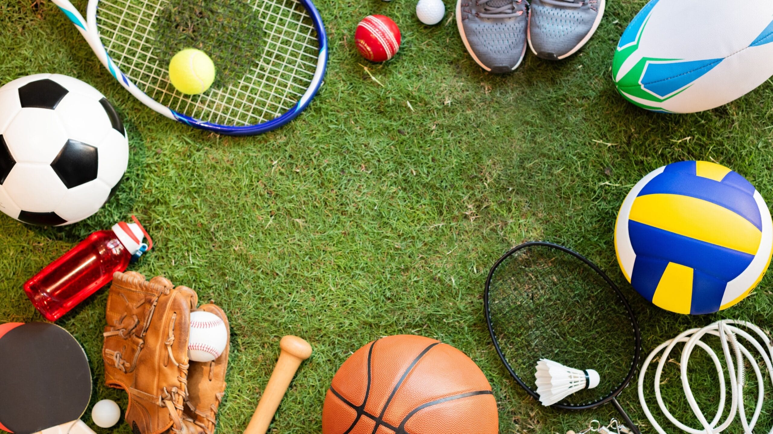 Image of green grass with lots of sports equipment around the edge