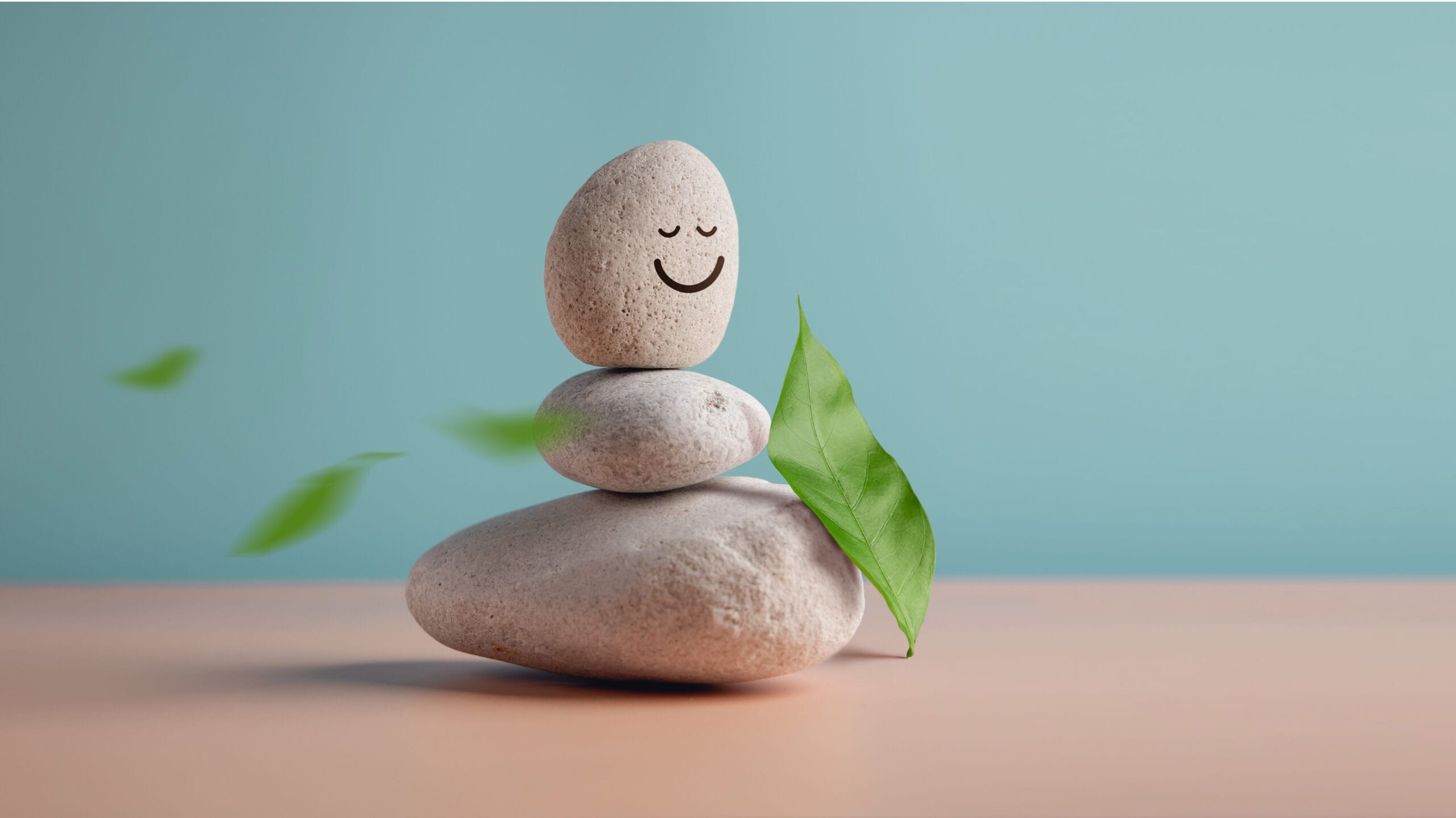 Alt text: rocks piled on top of one another against a blue background. A smiley face is drawn on the rock at the top.