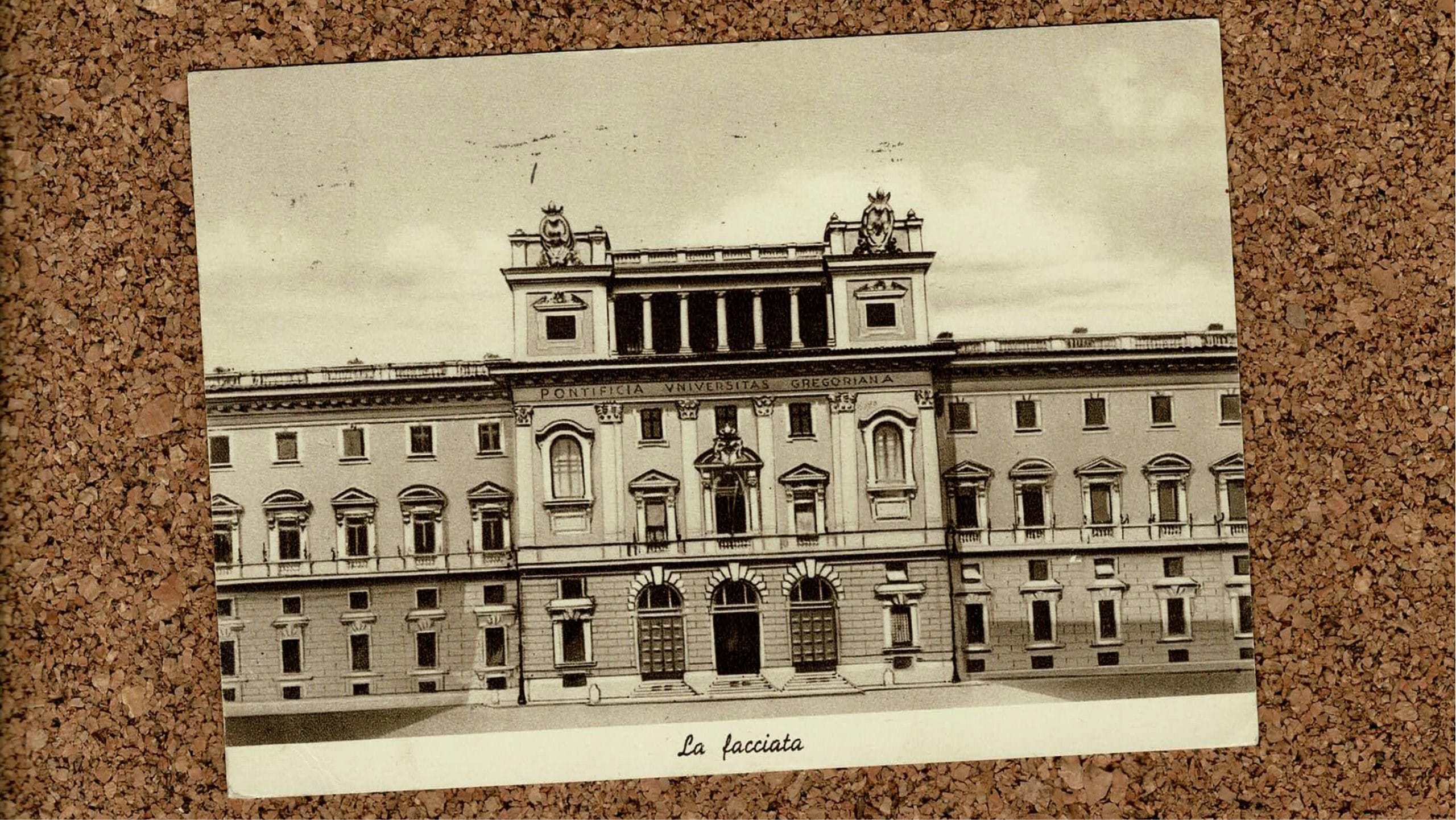 Image of a postcard of Pontifical Gregorian University on a cork board background