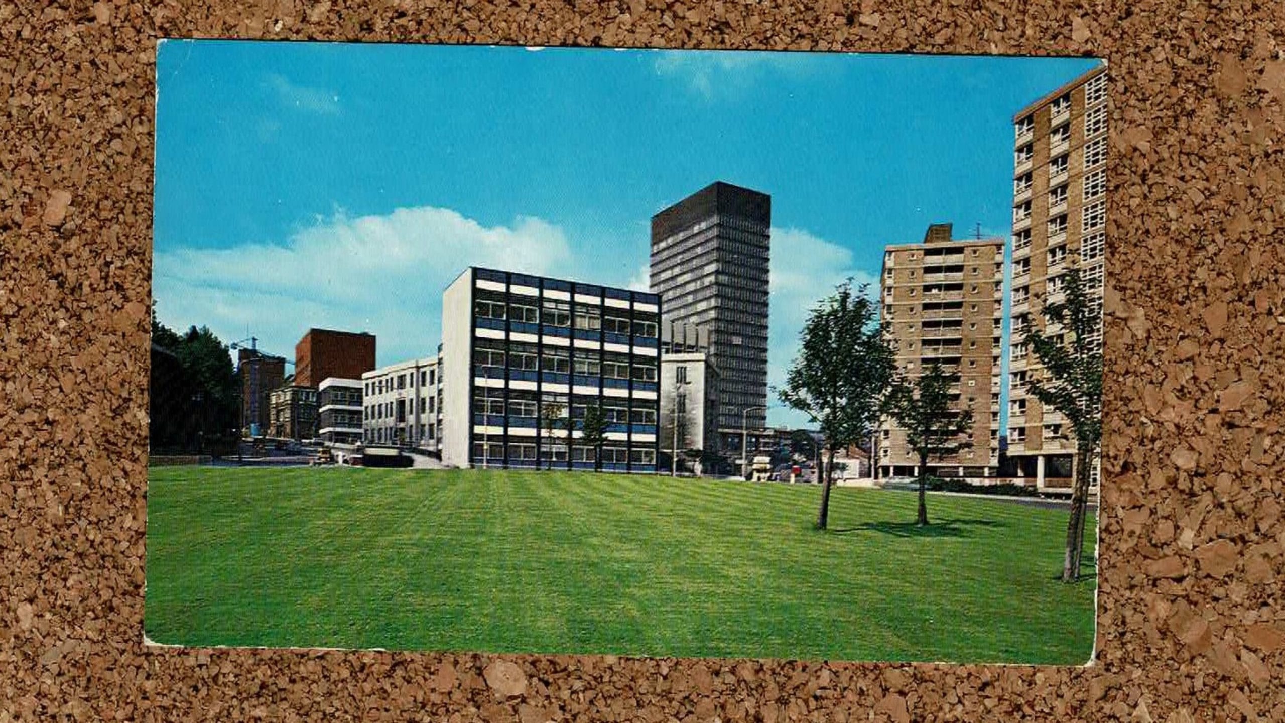 Cork board background with a postcard with an image of the Arts Tower at the University of Sheffield