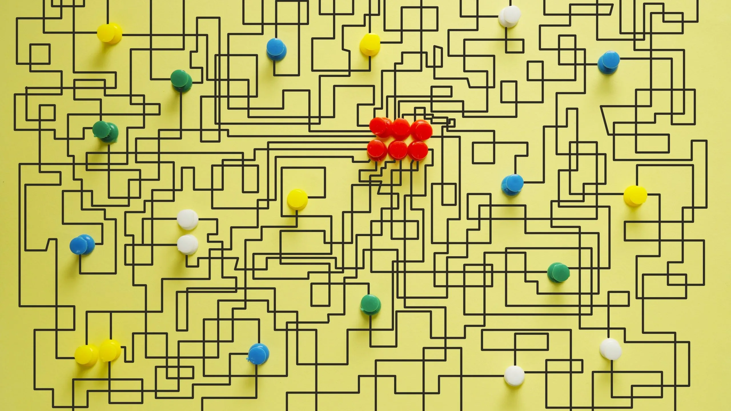 A yellow background with lots of pins and drawn lines scattered across
