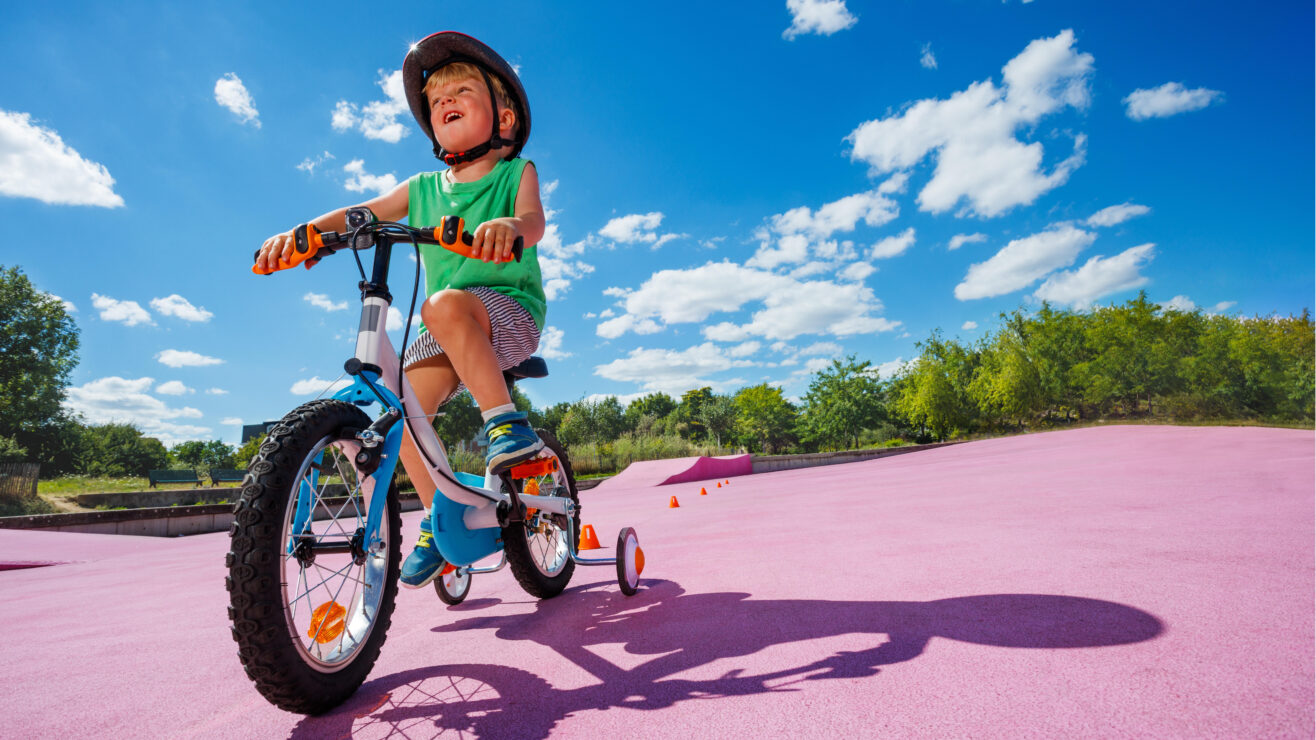 Happy,Little,Boy,Learning,To,Ride,Bicycle,With,Extra,Wheels,