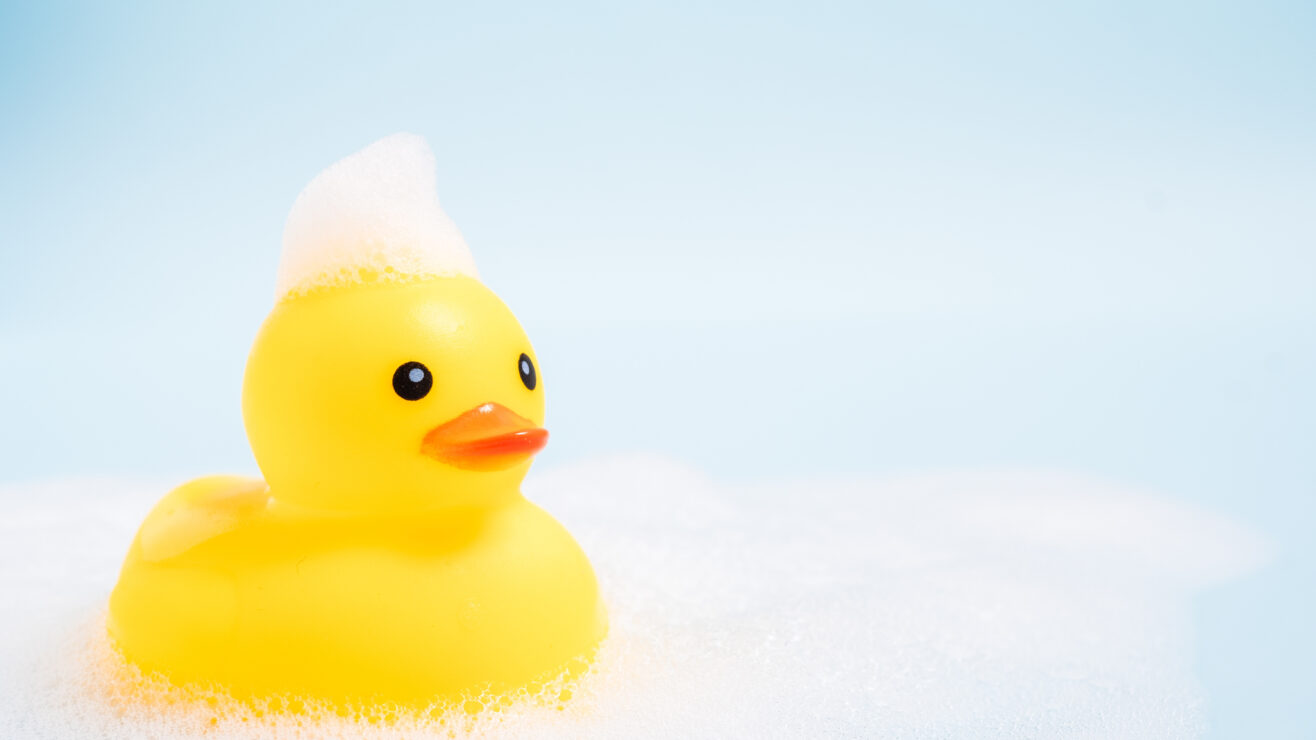 A,Yellow,Rubber,Duck,Is,Floating,In,A,Bathtub,Filled