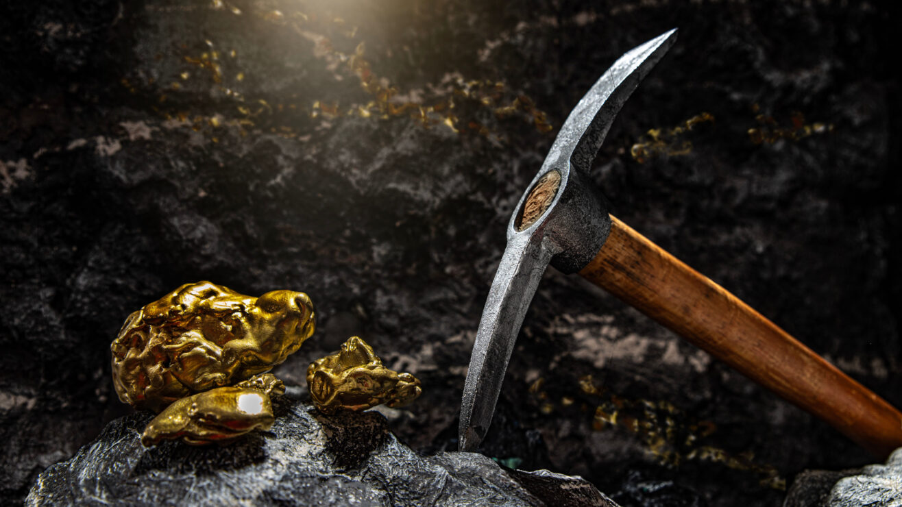 Pickaxe,And,Gold,Nuggets,Among,Stones,On,A,Background,Of